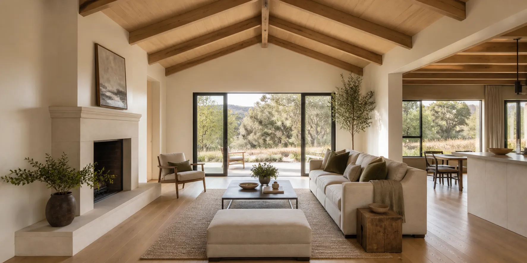 Vaulted living room with oak beams, limestone fireplace and black-framed doors to the garden
